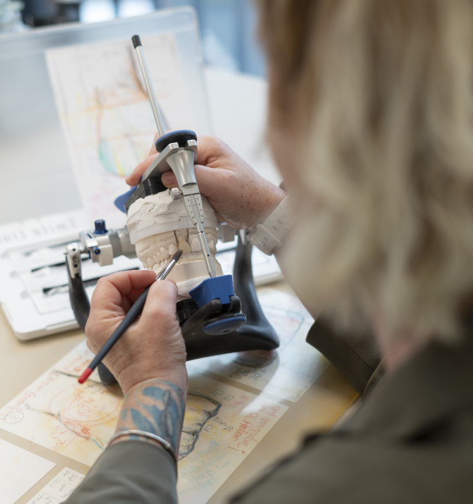 Unsere Labormitarbeiterin färbt einen Zahnersatz